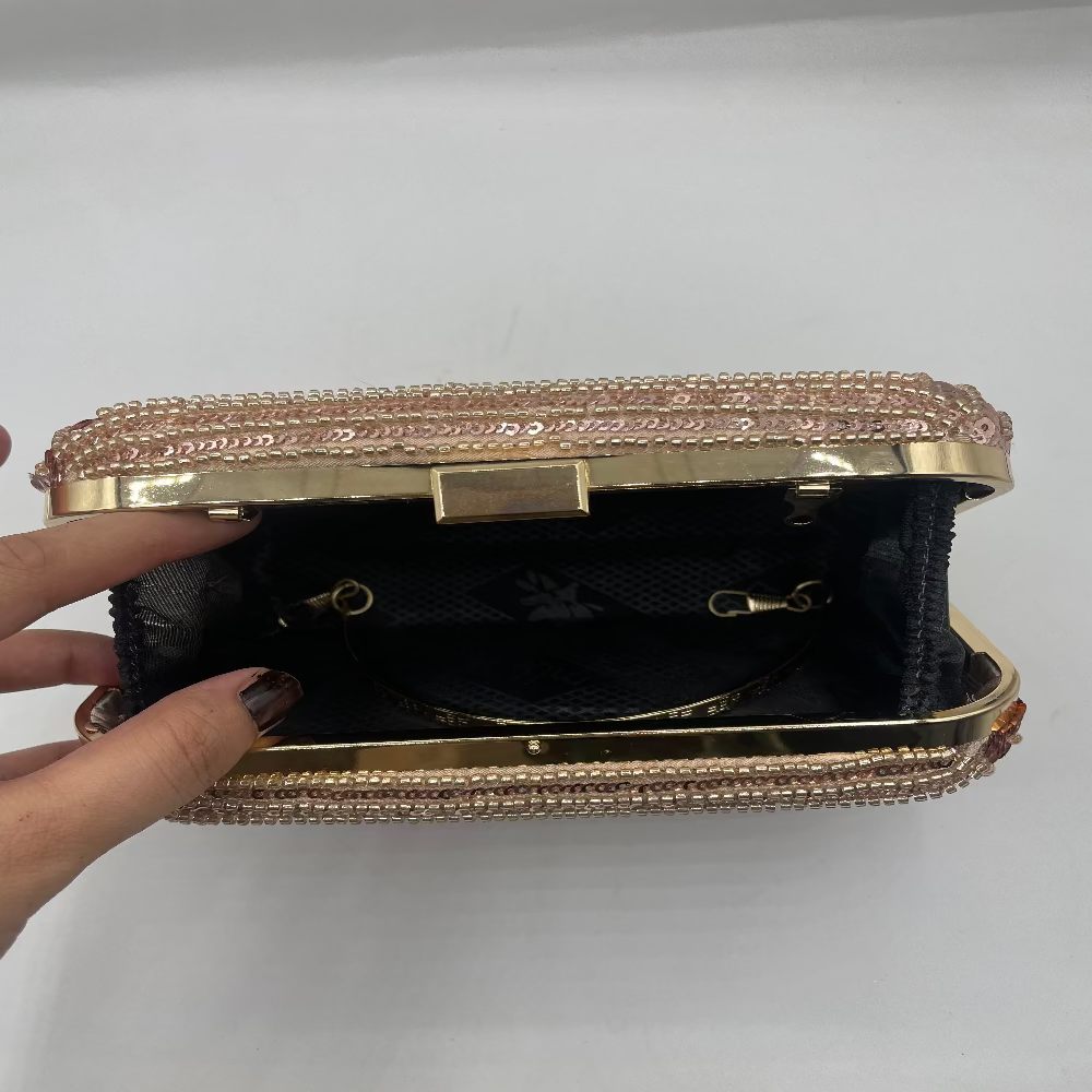Gold and black handbag with decorative trim on a white background