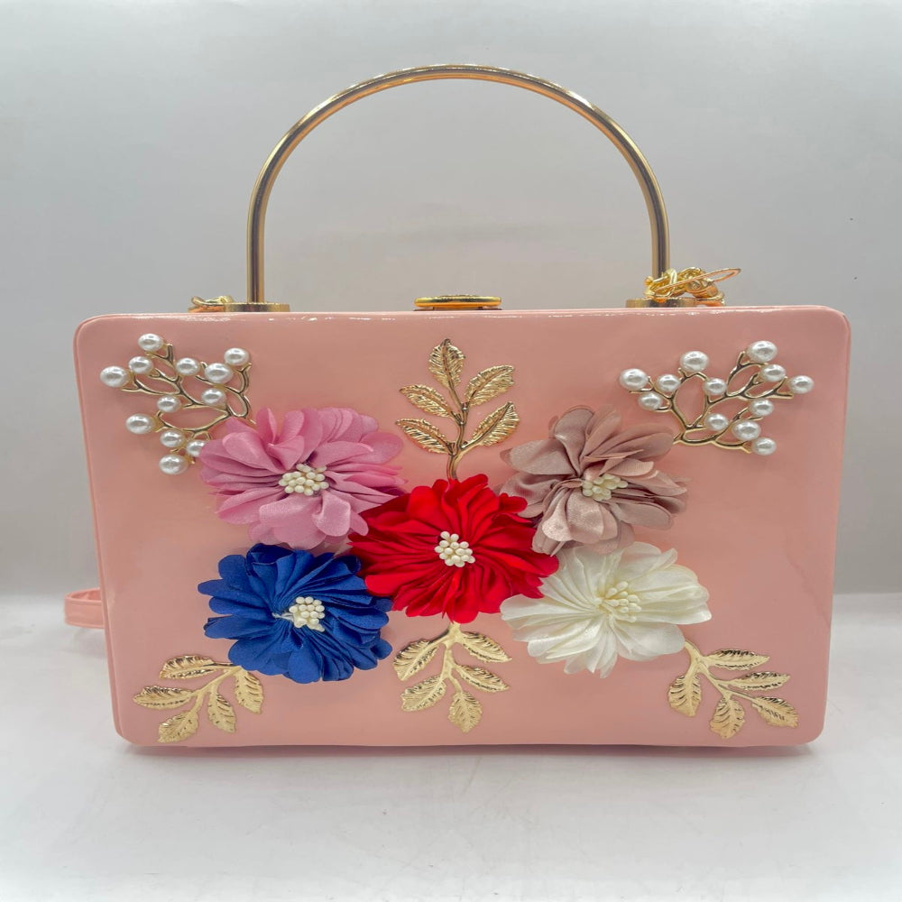 Pink handbag with floral decorations and a gold handle on a white background