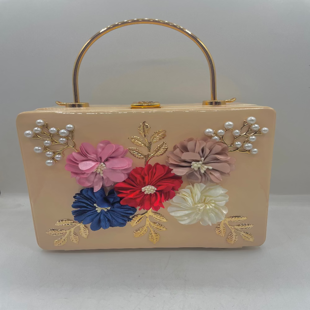 Beige handbag with floral decorations and pearl embellishments on a white background