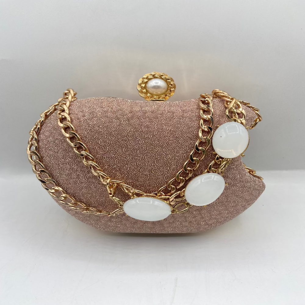 Pink handbag with gold chains and pearl-like stones on a white background
